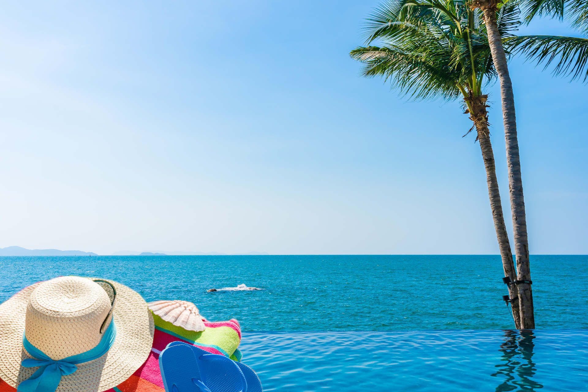 Blaues Meer mit Palmen, Sonnenhut und Strand